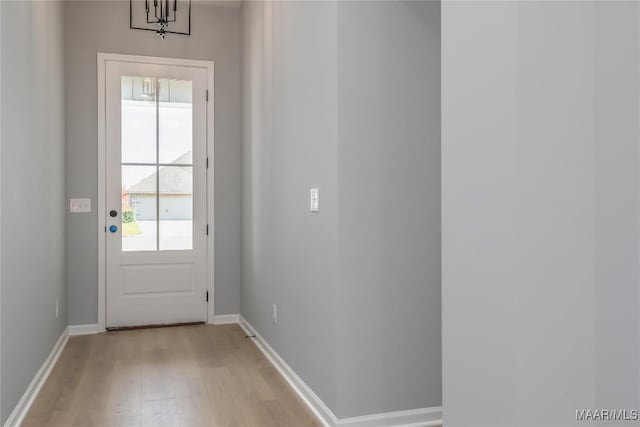 doorway to outside with an inviting chandelier and light hardwood / wood-style flooring