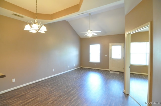 interior space featuring lofted ceiling, ceiling fan with notable chandelier, a raised ceiling, and dark wood-type flooring