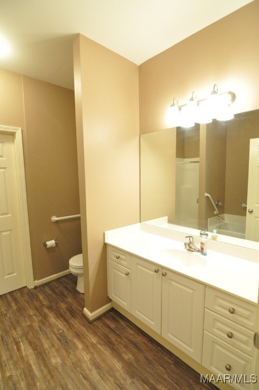 bathroom with a bathing tub, hardwood / wood-style floors, vanity, and toilet