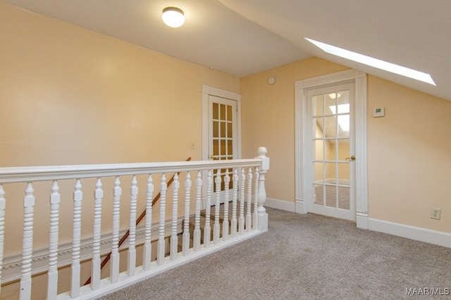 hall with carpet and lofted ceiling with skylight