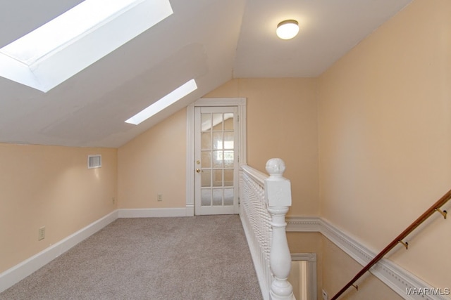 additional living space featuring lofted ceiling with skylight and light carpet