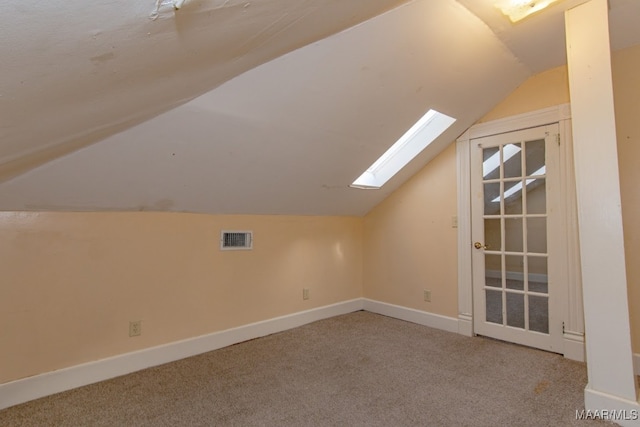 bonus room with vaulted ceiling with skylight and light carpet