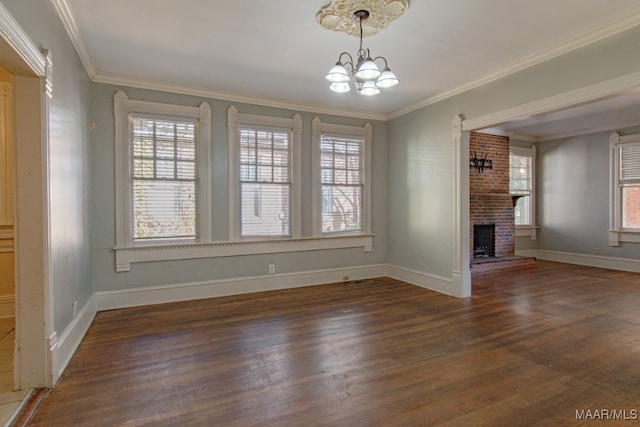 unfurnished living room featuring a fireplace, ornamental molding, dark hardwood / wood-style floors, and a notable chandelier