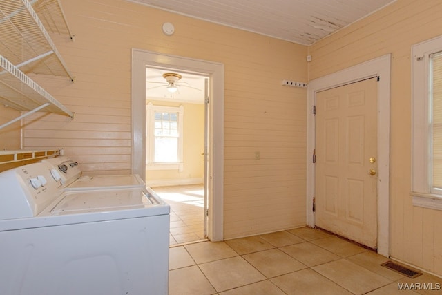 washroom with wooden walls, washer and clothes dryer, light tile patterned floors, and ceiling fan