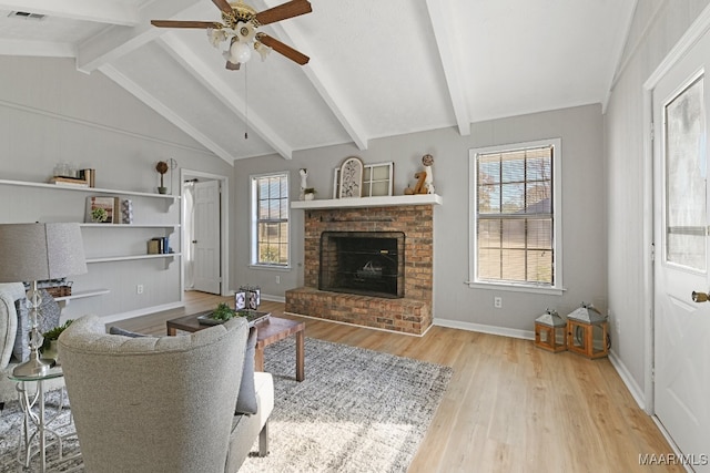 living room featuring a fireplace, lofted ceiling with beams, light hardwood / wood-style flooring, and a wealth of natural light