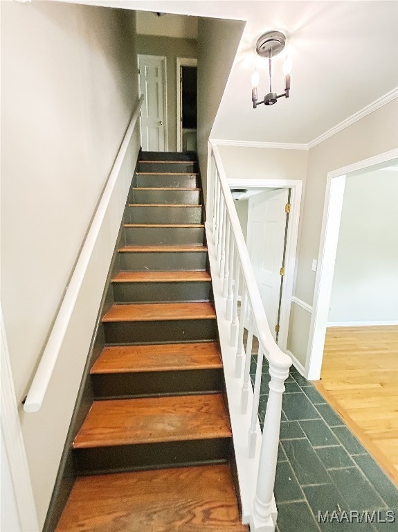 staircase with hardwood / wood-style floors, an inviting chandelier, and ornamental molding