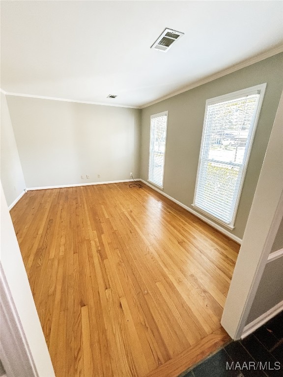 empty room featuring hardwood / wood-style floors, plenty of natural light, and crown molding