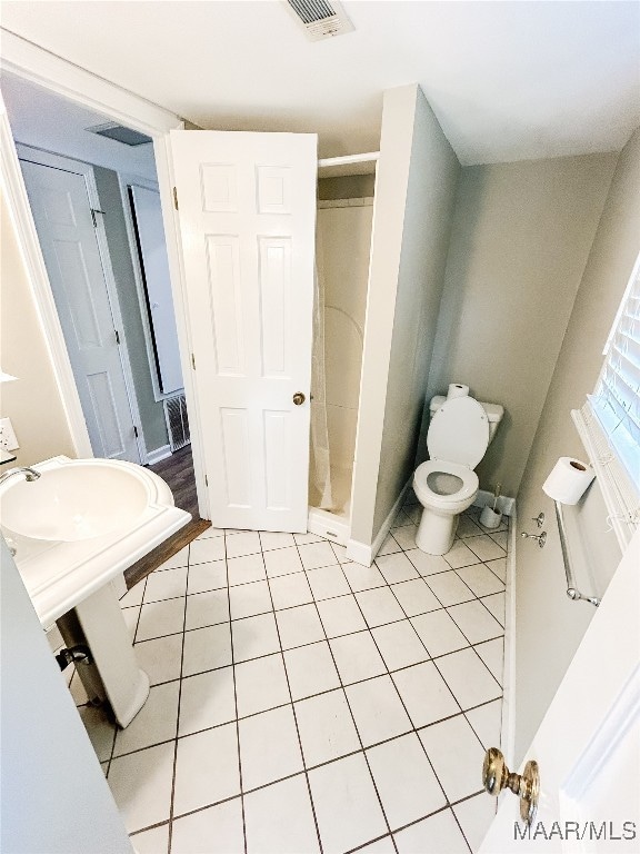 bathroom with tile patterned floors, toilet, and a shower