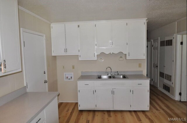 12 Pine St, Montgomery, AL 36110 - kitchen with a sink, light wood-style flooring, white cabinetry, light countertops, and a textured ceiling