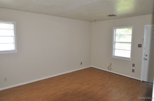 spare room with a textured ceiling and hardwood / wood-style flooring