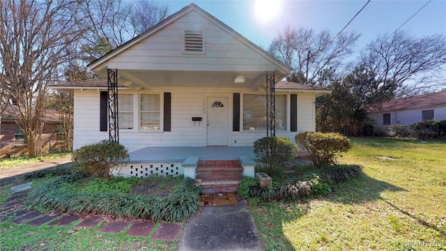 bungalow with covered porch and a front lawn