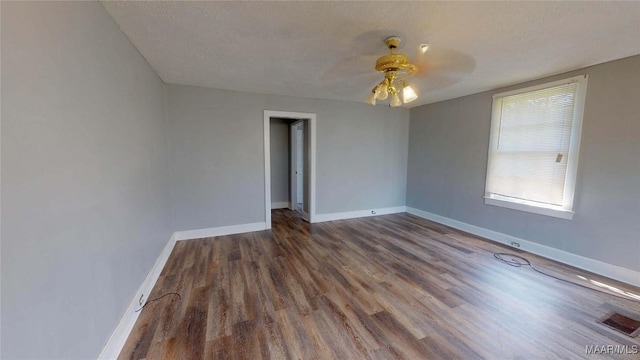 unfurnished room featuring ceiling fan, dark wood-type flooring, and a textured ceiling