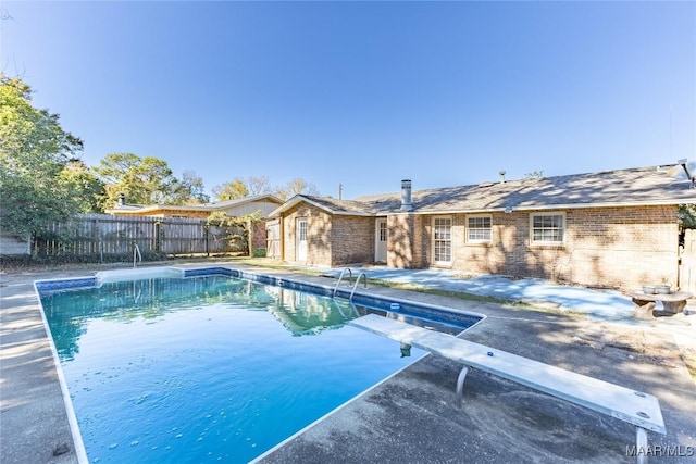 view of pool with a diving board and a patio area