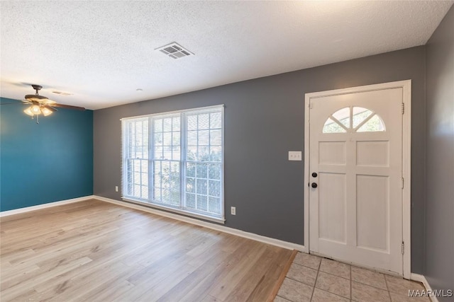 entryway featuring ceiling fan, light wood-type flooring, and a textured ceiling