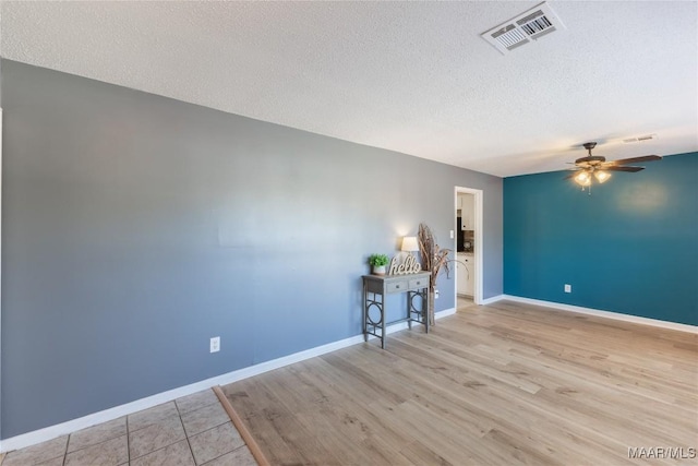 empty room featuring ceiling fan, a textured ceiling, and light hardwood / wood-style flooring