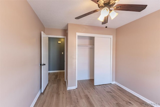 unfurnished bedroom featuring a textured ceiling, a closet, light hardwood / wood-style floors, and ceiling fan