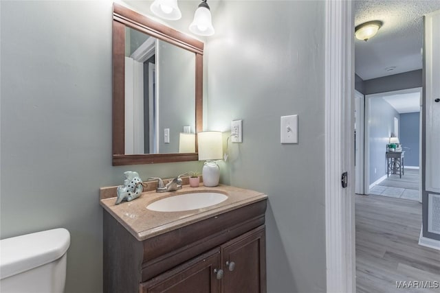 bathroom featuring hardwood / wood-style floors, vanity, a textured ceiling, and toilet