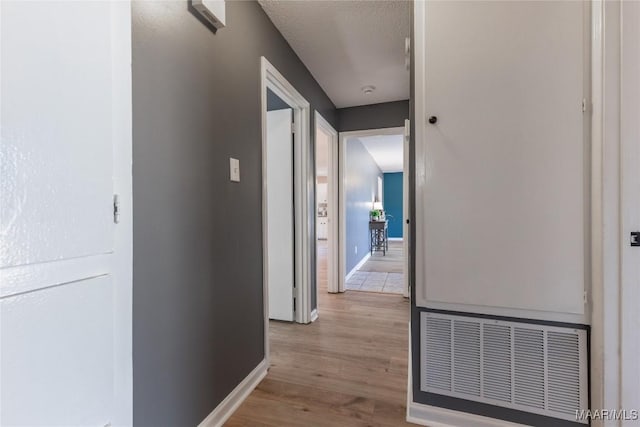 corridor featuring a textured ceiling and light hardwood / wood-style flooring