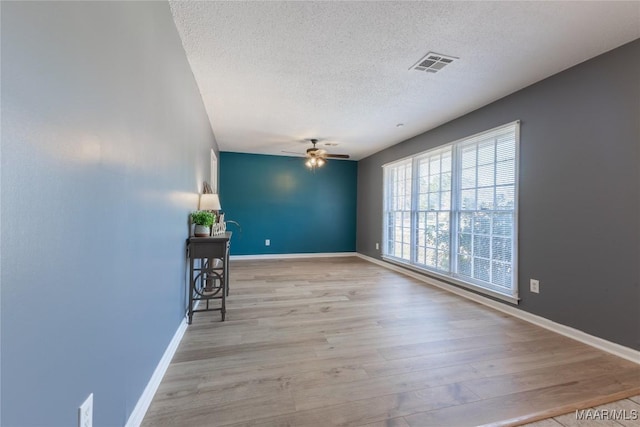 spare room featuring ceiling fan, light hardwood / wood-style flooring, and a textured ceiling