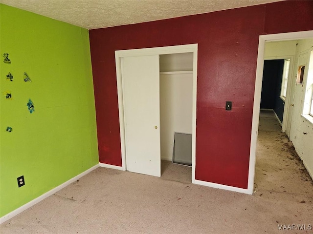 unfurnished bedroom with light carpet, a closet, and a textured ceiling