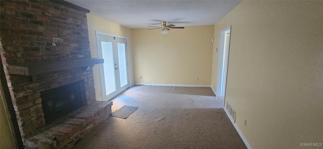 unfurnished living room with carpet flooring, ceiling fan, a large fireplace, and a textured ceiling