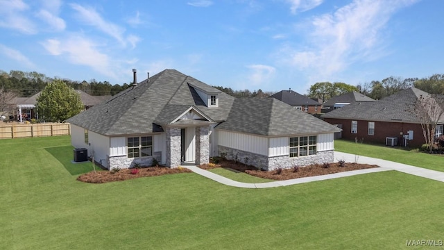view of front of house with a front yard, a shingled roof, and stone siding