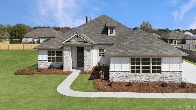 view of front facade featuring fence, board and batten siding, a shingled roof, and stone siding