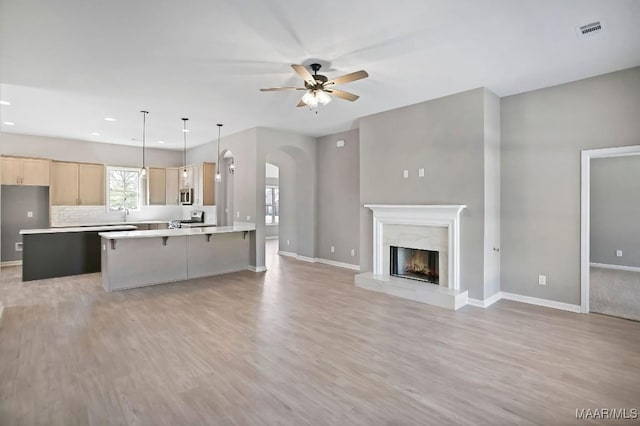 kitchen featuring light brown cabinetry, baseboards, light wood-type flooring, and a ceiling fan