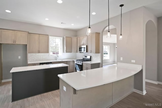 kitchen featuring tasteful backsplash, stainless steel appliances, a peninsula, and arched walkways
