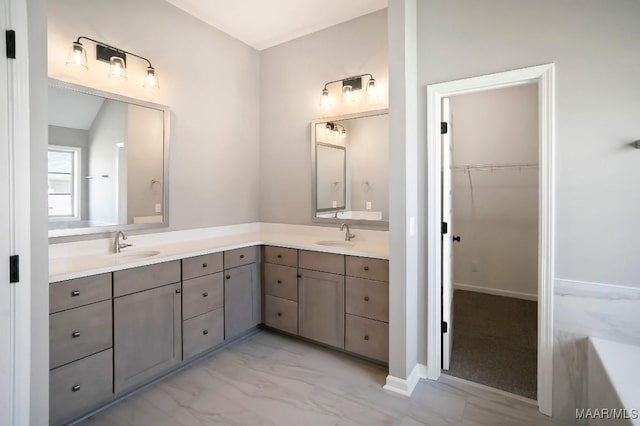 full bath featuring double vanity, a spacious closet, and marble finish floor
