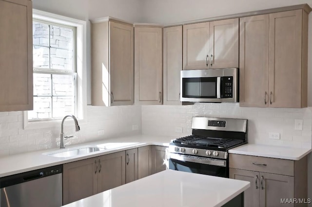 kitchen with a sink, tasteful backsplash, stainless steel appliances, and light countertops