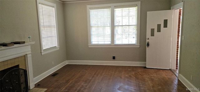 unfurnished living room featuring a tile fireplace, crown molding, and dark hardwood / wood-style floors