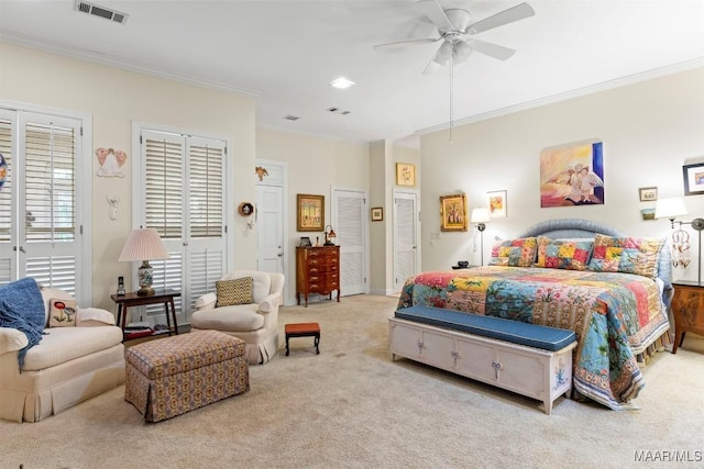 bedroom featuring ceiling fan, crown molding, light carpet, and multiple closets