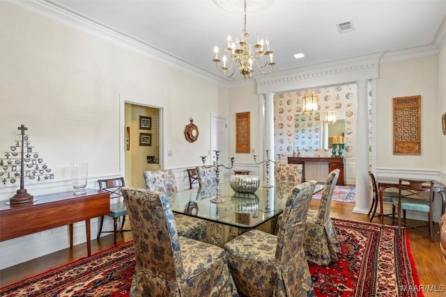 dining area featuring wood-type flooring, ornamental molding, and an inviting chandelier