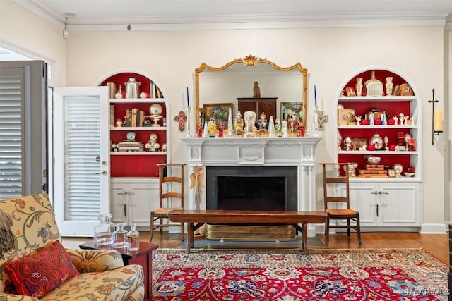 living area with crown molding, built in features, and hardwood / wood-style flooring