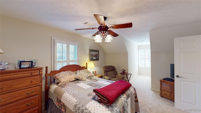 bedroom with ceiling fan, light colored carpet, lofted ceiling, and a textured ceiling