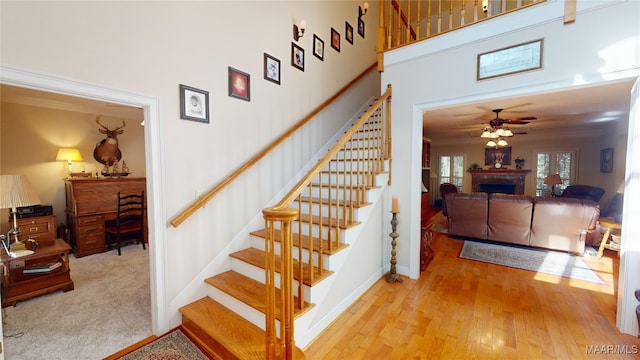 stairs featuring ceiling fan, wood-type flooring, and crown molding