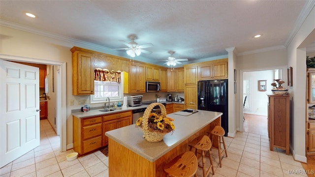 kitchen with crown molding, sink, light tile patterned floors, an island with sink, and appliances with stainless steel finishes