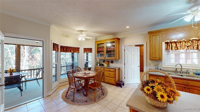 tiled dining space featuring ceiling fan, sink, a textured ceiling, and ornamental molding