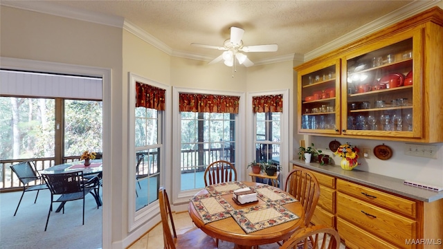 carpeted dining space featuring plenty of natural light, ceiling fan, and ornamental molding