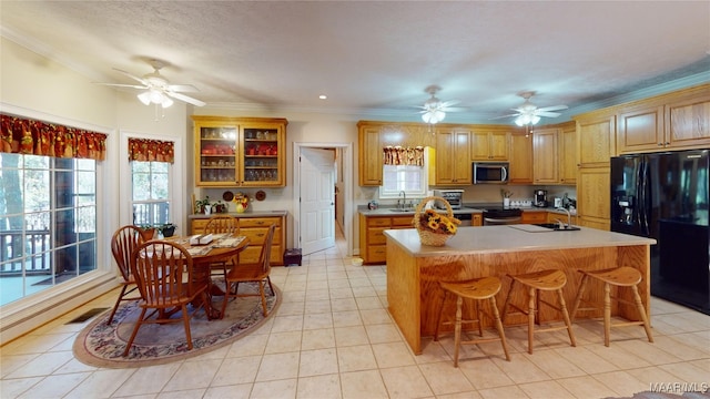 kitchen featuring a center island, sink, crown molding, light tile patterned floors, and stainless steel appliances