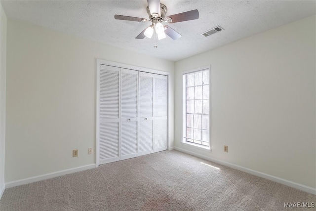 unfurnished bedroom featuring ceiling fan, a closet, a textured ceiling, and carpet