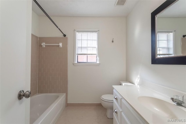 full bathroom with tile patterned flooring, vanity, tiled shower / bath, and toilet