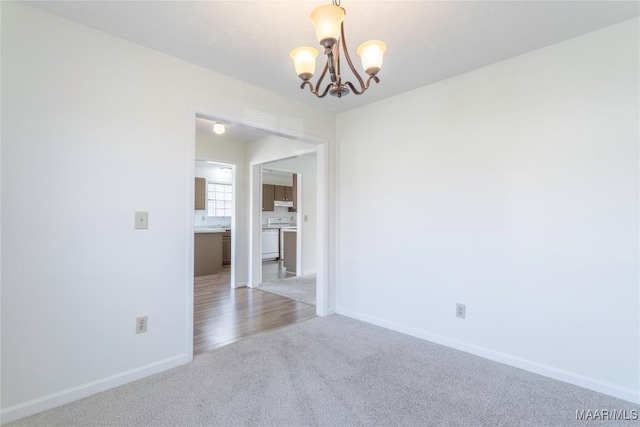 carpeted empty room with a chandelier