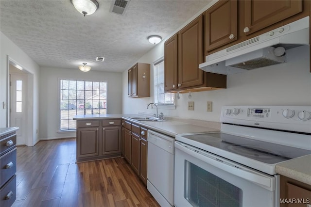 kitchen with sink, white appliances, kitchen peninsula, dark wood-type flooring, and a textured ceiling