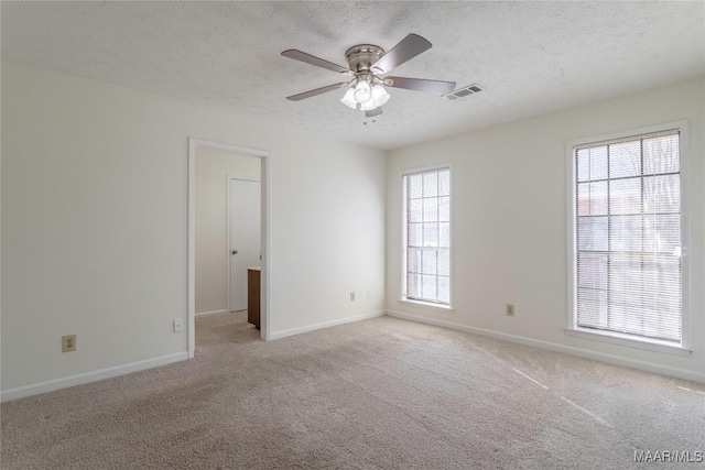 carpeted empty room featuring ceiling fan and a textured ceiling