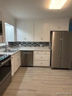 kitchen with sink, tasteful backsplash, light hardwood / wood-style floors, white cabinets, and appliances with stainless steel finishes