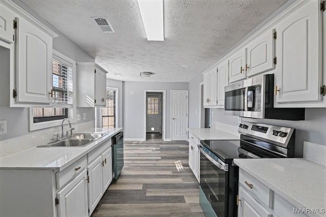 kitchen featuring sink, dark hardwood / wood-style floors, a textured ceiling, white cabinets, and appliances with stainless steel finishes