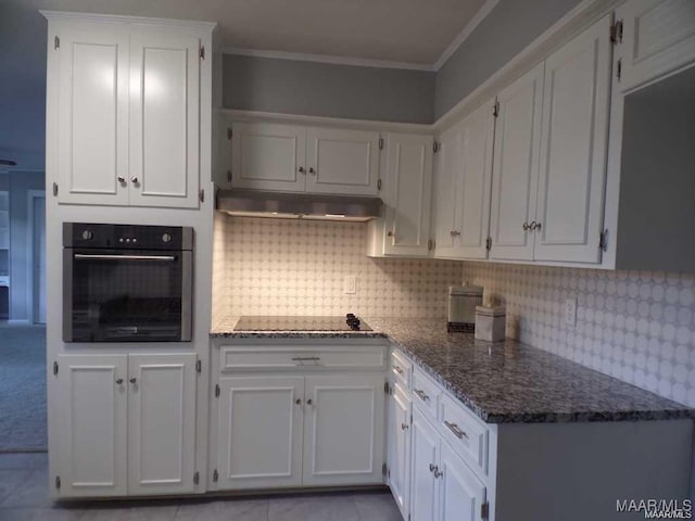 kitchen featuring dark stone counters, ornamental molding, stainless steel oven, black electric cooktop, and white cabinets