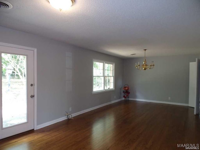 unfurnished room featuring a textured ceiling, a chandelier, and dark hardwood / wood-style floors